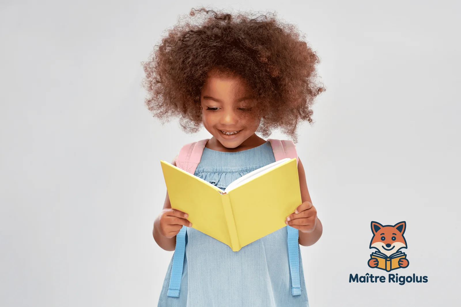 Une jeune fille sourit en lisant un livre jaune